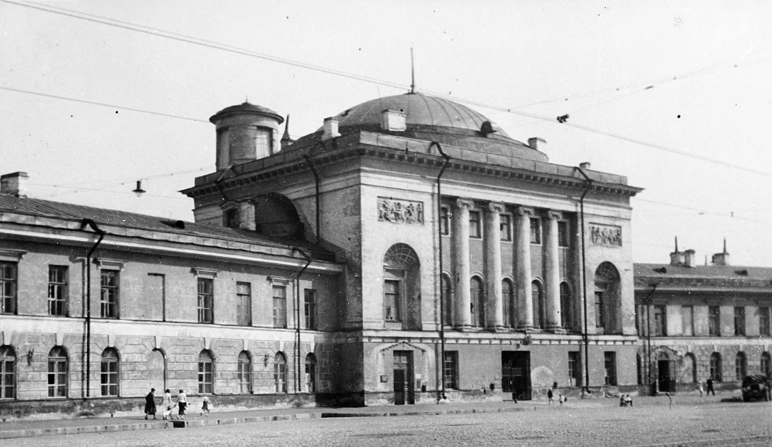 Старое фото: церковь с куполом и колоннами, слева длинный корпус, перед ними булыжная площадь
