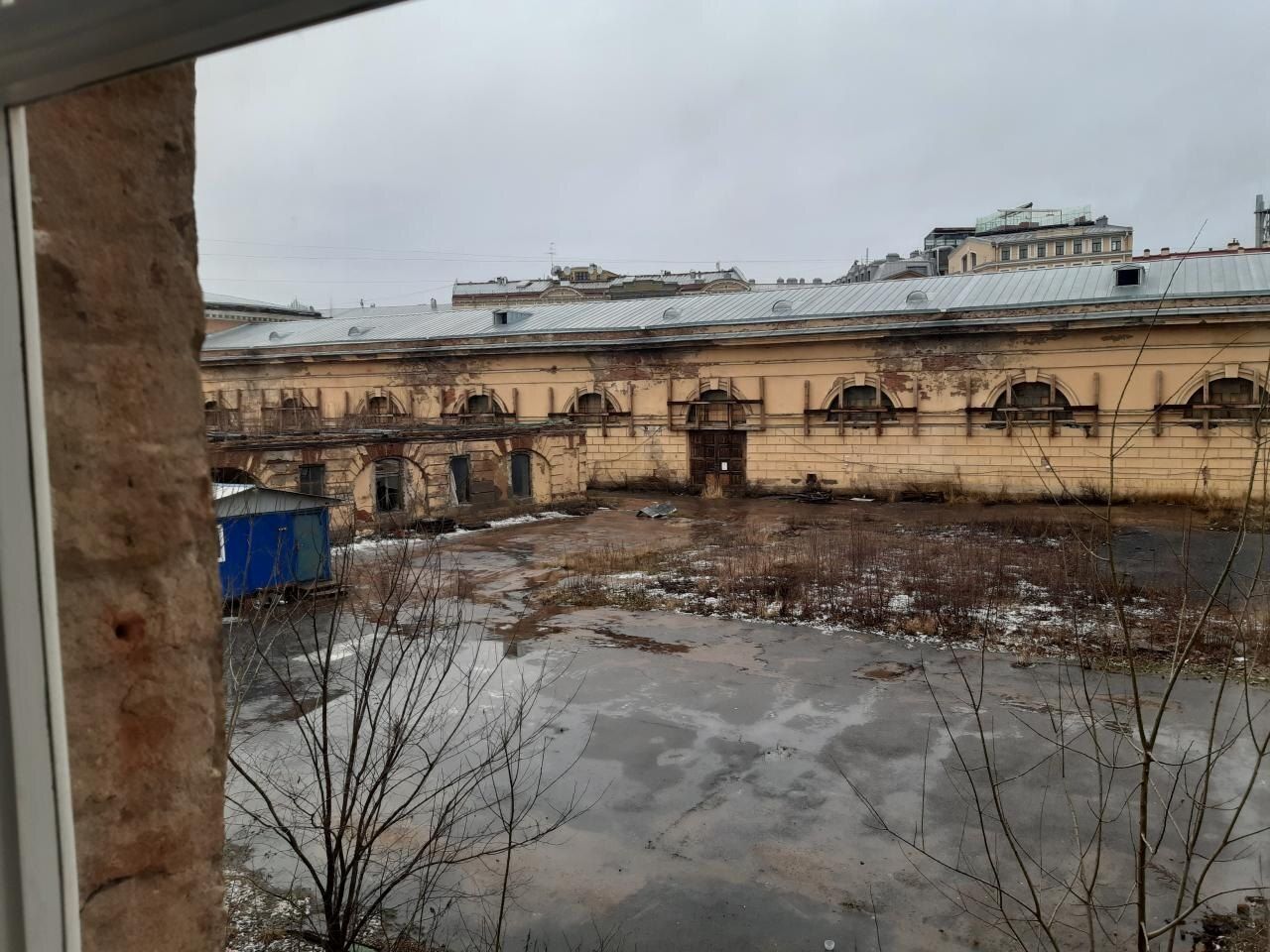 Заброшенный двор Конюшенного ведомства — лужи, мусор, корпуса с облупившейся штукатуркой